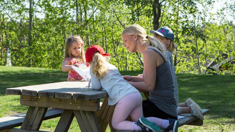 Barn sitter på en bänk ute på gården. Barn sitter på en bänk ute på gården.